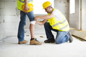 construction accident lawyer in Buffalo, NY construction worker helping to place bandage wrap on other worker's injured knee